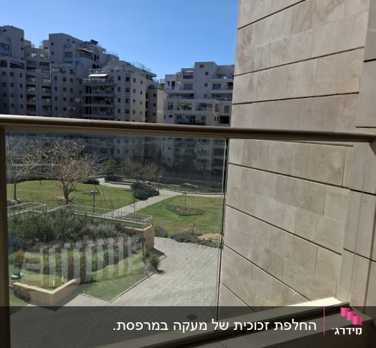 מעקה זכוכית שקוף במרפסת דירה המשקיפה לפארק